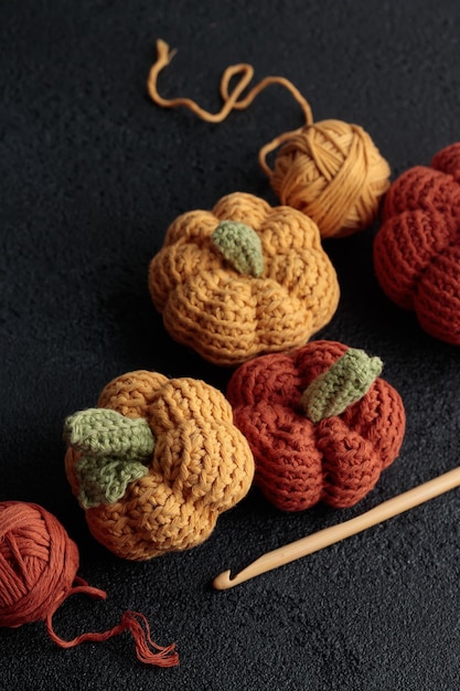 Cute crochet knitted yellow and orange pumpkins on black background