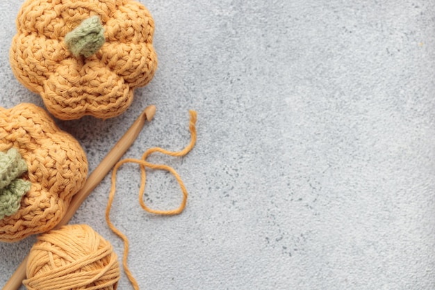 Cute crochet knitted yellow pumpkins on gray background