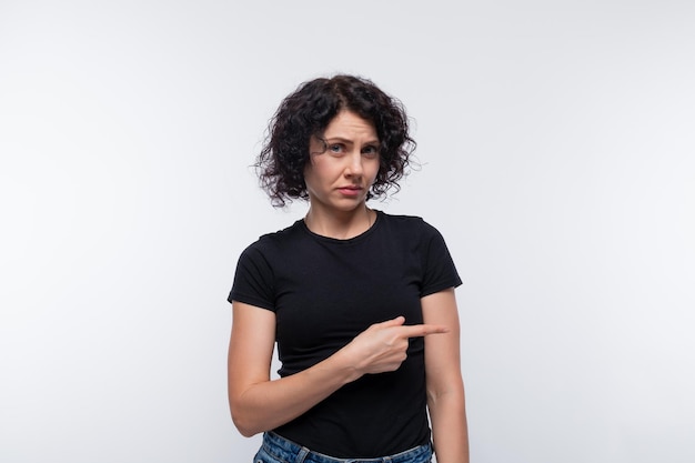 Cute curly European woman in a black Tshirt against a studio background