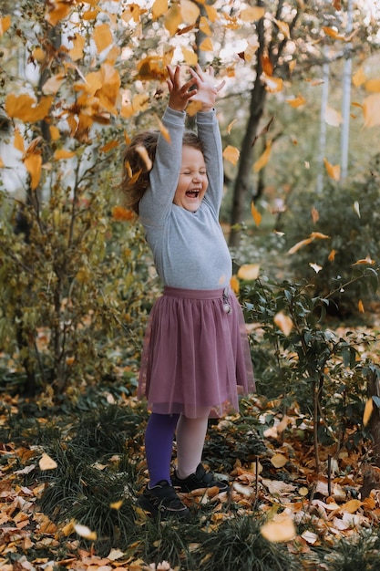 cute curly hair little girl throwing leaves in park at fall time autumn banner card healthcare