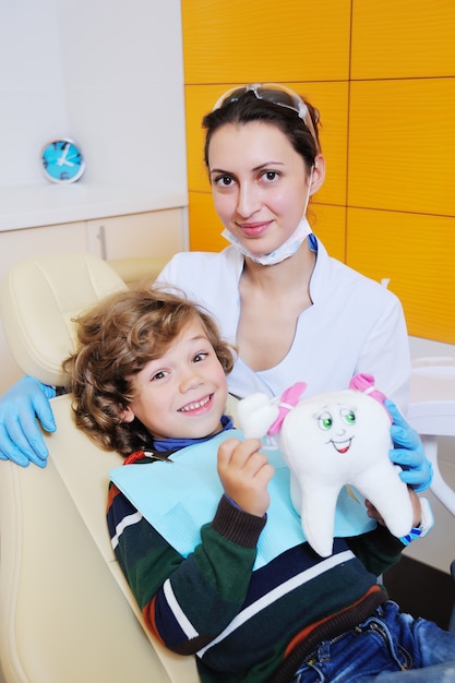 Foto un bambino carino, dai capelli ricci si concede e fa una smorfia su una poltrona del dentista