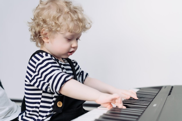 ピアノを弾くかわいい巻き毛の小さな男の子