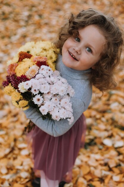 милая кудрявая маленькая девочка в синей рубашке в парке с цветами осенью баннер осенней карты здоровья