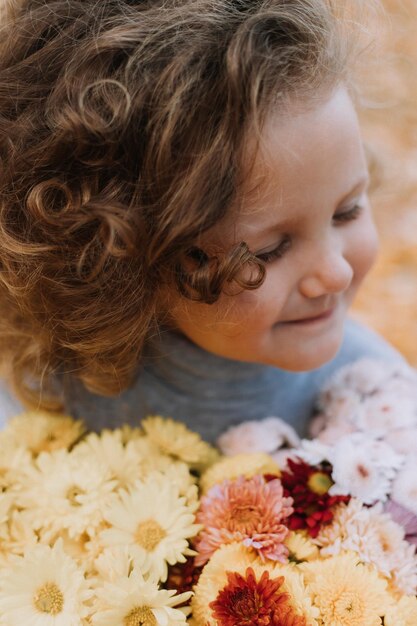 가을 건강 카드 배너에 꽃과 함께 공원에 파란색 셔츠를 입은 귀여운 곱슬 소녀