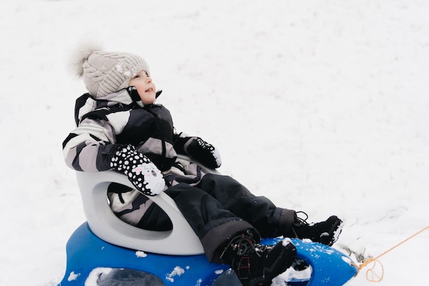 雪のアクティブなライフスタイルの冬の家族のそりでかわいいかわいい男の子