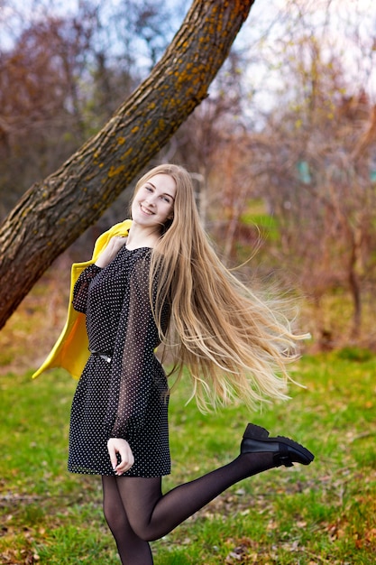 Cute cute girl with long hair in a yellow coat