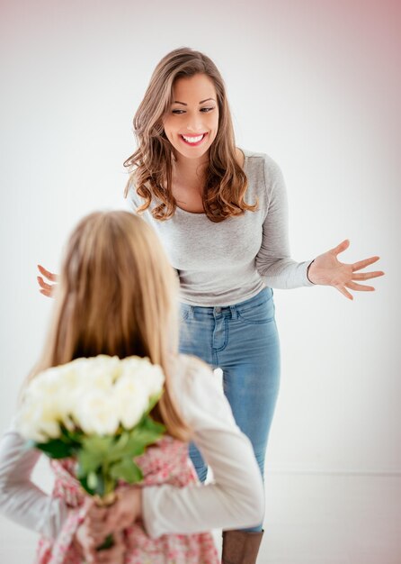Милая дочь дарит маме букет белых роз на День матери. Выборочный фокус. Сосредоточьтесь на фоне, на маме.