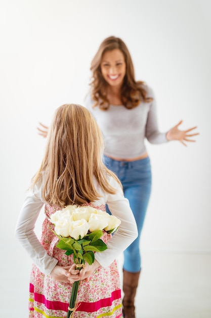 Foto figlia carina che dà a sua madre un bouquet di rose bianche per la festa della mamma. messa a fuoco selettiva. concentrati sul primo piano, sulla bambina e sui fiori.