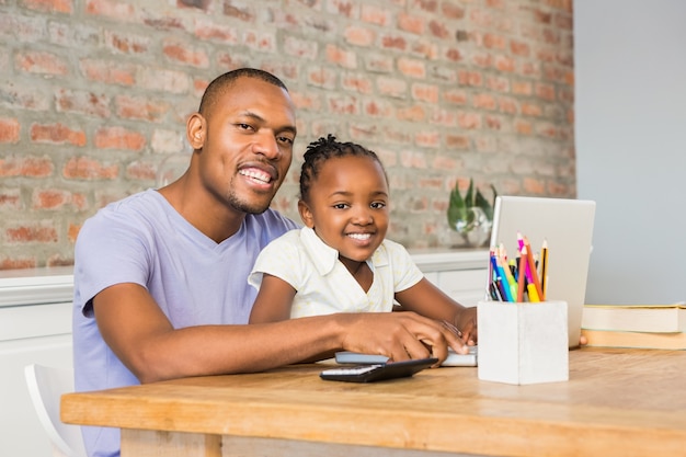 Cute daughter using laptop at desk with father