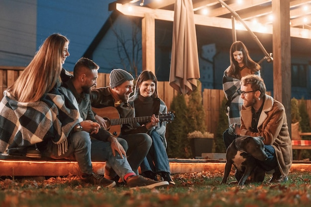 cute dog group of people is spending time together on the backyard at evening time