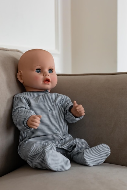 Photo cute doll dolls in a blue bodysuit sitting on a beige sofa