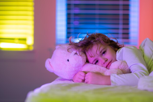 写真 ベッド就寝時の子供時代と成長の子供の概念 closeu でおもちゃのテディベアとかわいい眠そうな眠い子