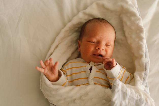 Cute emotional newborn little baby boy in crib.