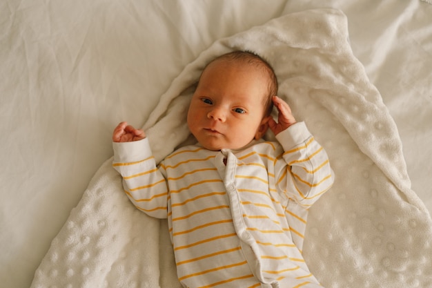 Cute emotional newborn little baby boy in crib. 