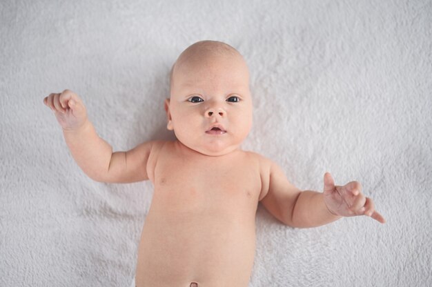 Cute emotional smiling funny newborn boy laying on bed