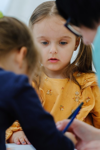 Cute european kid girl painting with colored pencil Kindergarten children education concept