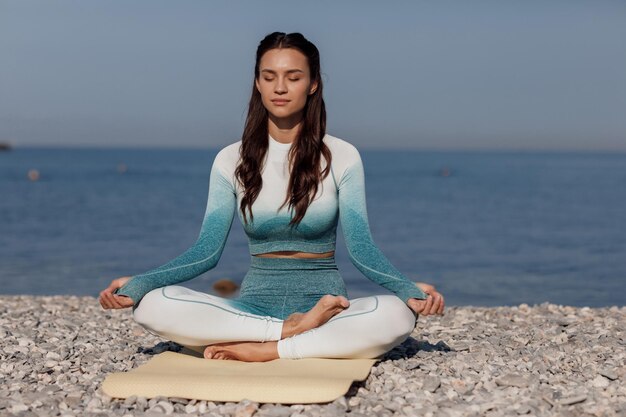 cute female doing yoga on the beach near the sea