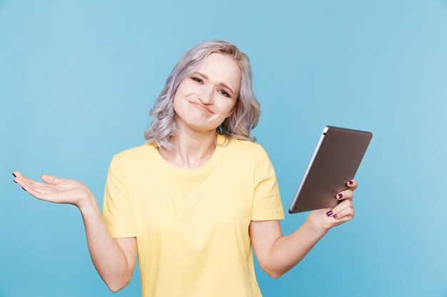 Cute female holding tablet with funny face isolated