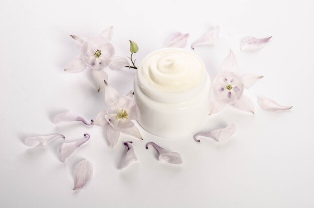 Cute flowers and petals and a jar of natural body cream isolated