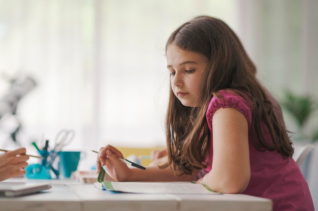 Cute focused girl sitting at desk and studying