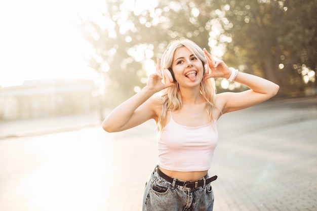 Cute fun girl listening to music on headphones in the city