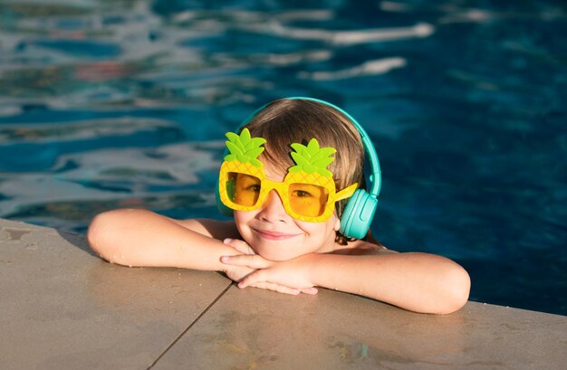 Foto carina faccia divertente di un ragazzino con degli occhiali da sole divertenti in piscina in una giornata di sole