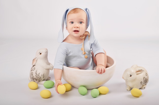 Cute funny baby boy with bunny ears and colorful Easter eggs and rabbits. Easter Baby. Greeting Easter card template.