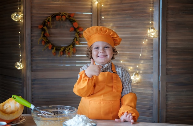 Cute funny boy in a chef costume shows a like gesture. little chef in the kitchen