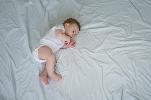 Photo cute funny newborn little boy peacefully sleeping on white sheets in bed or crib baby goods