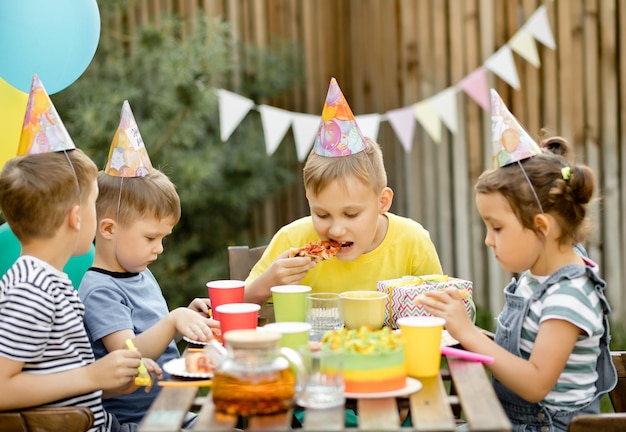 Cute funny nine year old boy celebrating his birthday with family or friends and eating homemade baked pizza in a backyard Birthday party for kids