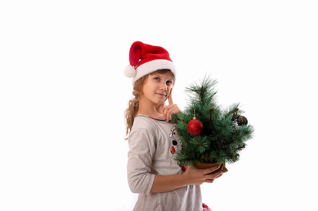 Cute funny Santa's helper shows a Christmas tree toy on a white background. The concept of Christmas holidays. New year celebration.
