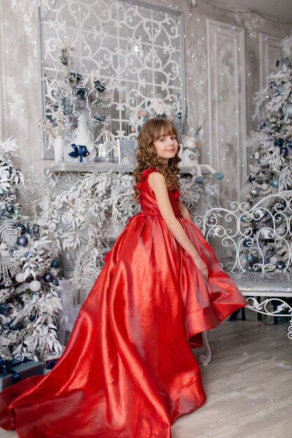 Cute girl in anticipation of the new year and Christmas 2022 in an elegant dress with gifts