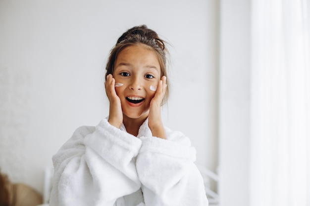 Cute girl applying face cream