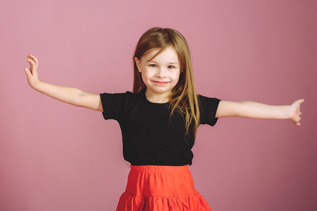 Photo cute girl in a black tank top and red skirt on a pink pastel background