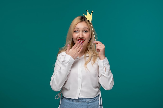 Cute girl blonde beautiful young girl in a white neat shirt covering mouth and excited