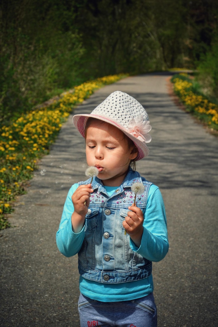 Photo cute girl blowing dandelion on road