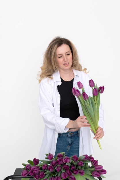 A cute girl collected a bouquet of purple tulips Stands on a white background