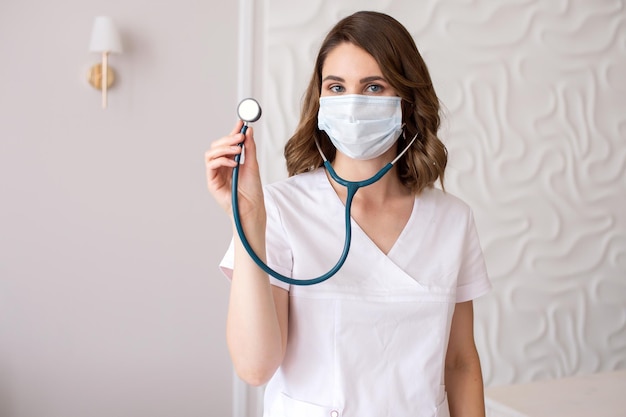 Cute girl doctor in a medical mask shows a stethoscope