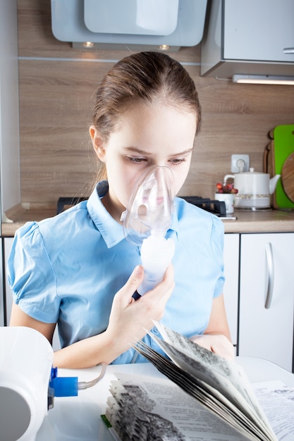 Cute girl doing inhalation and reading book in the kitchen