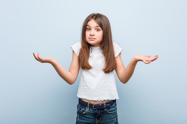 Cute girl doubting and shrugging him shoulders in questioning gesture.