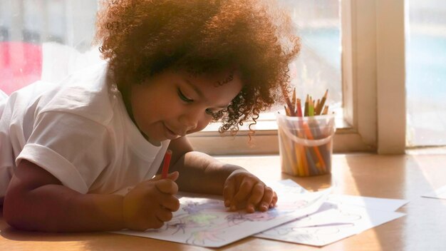 Photo cute girl drawing in paper while lying on floor at home