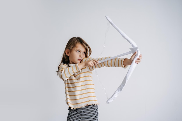 Cute girl drawing a selfmade toy paper bow with scotch tape string