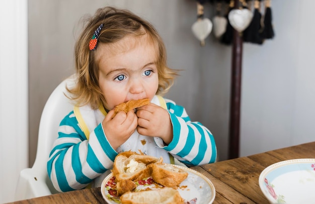 Foto ragazza carina che mangia pane a casa