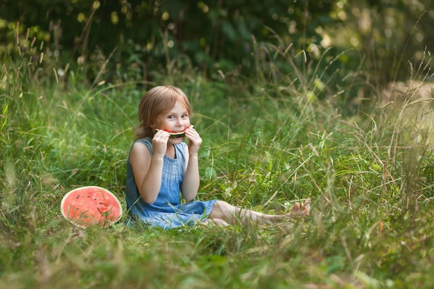 夏の屋外でスイカを食べるかわいい女の子子供のための健康的なスナック