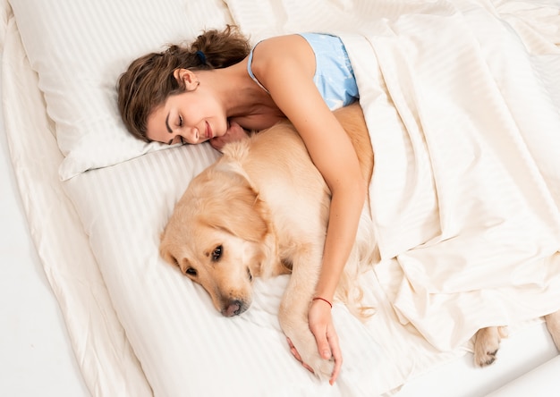 Cute girl embrace her own dog retriever in bedroom indoors