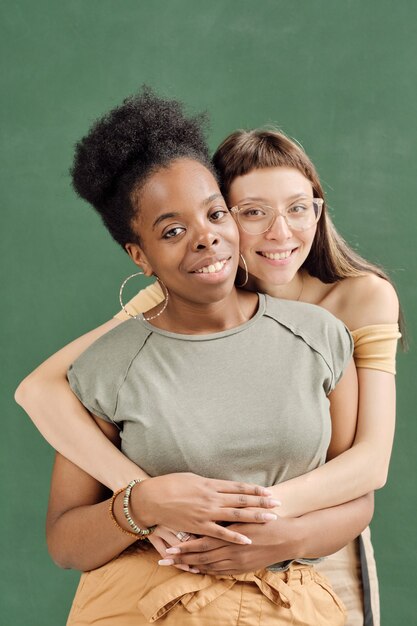 彼女のアフリカのガールフレンドを抱きしめる眼鏡のかわいい女の子