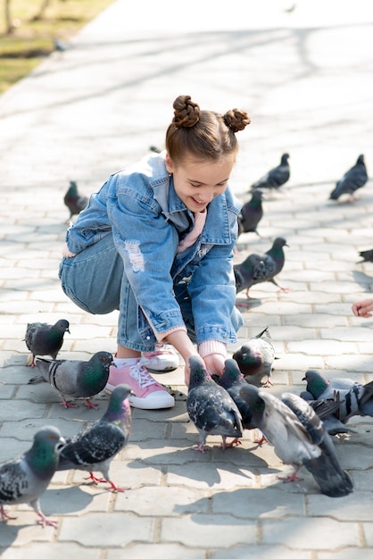 A cute girl feed feeds pigeons in the park.