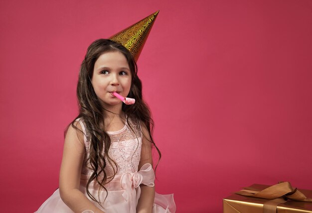 Cute girl in a festive hat on a pink background