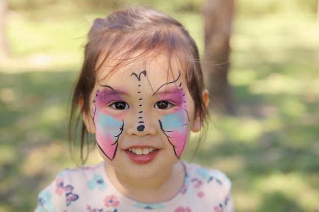 Foto ragazza sveglia che ottiene faccia dipinta come una farfalla