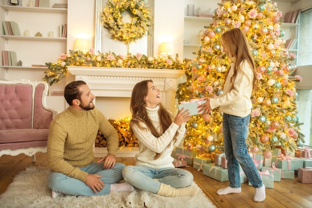 Cute girl giving new year present to her parents